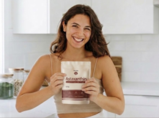 Customer holding a pouch of Reya Organics Astaxanthin in a bright kitchen