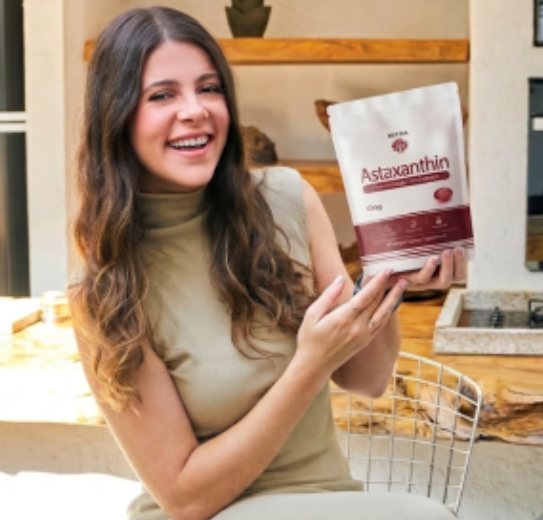 Customer smiling while holding a pouch of Reya Organics Astaxanthin